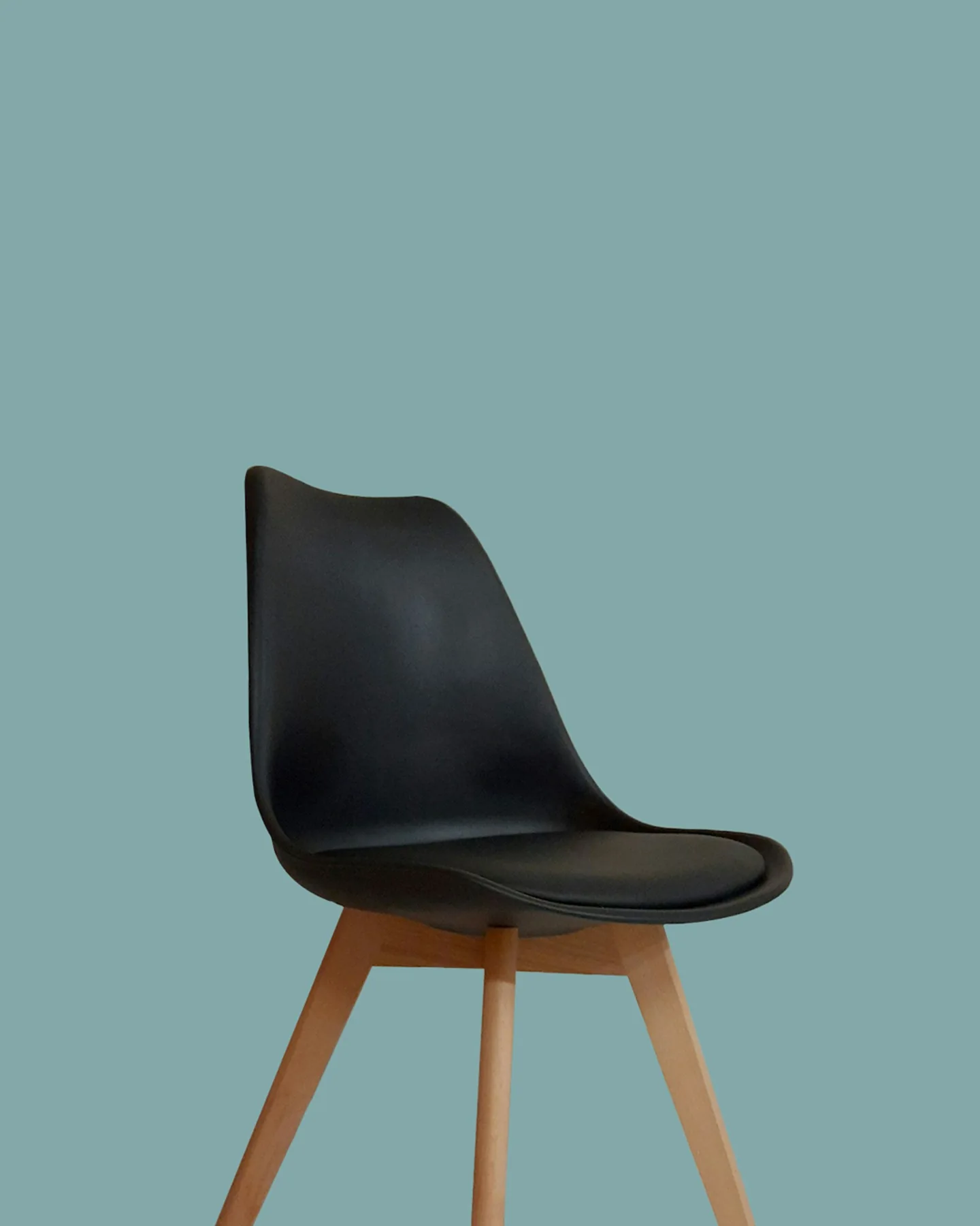 Black moulded side chair with timber legs against a muted blue wall